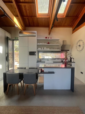 Una cucina moderna con isola centrale, elettrodomestici integrati e zona pranzo con tavolo e sedie.