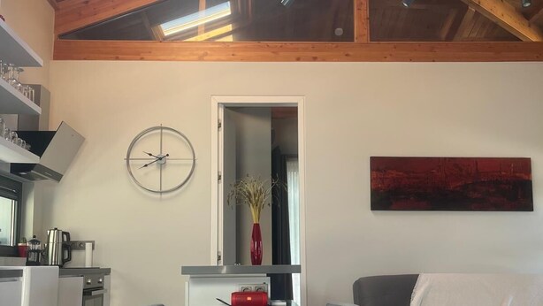 A modern living room with a dining table, grey sofa, and a red vase on the wall. - Elmalı Guest House 
A simple, serene, and deeply peaceful life awaits you! (Muğla)