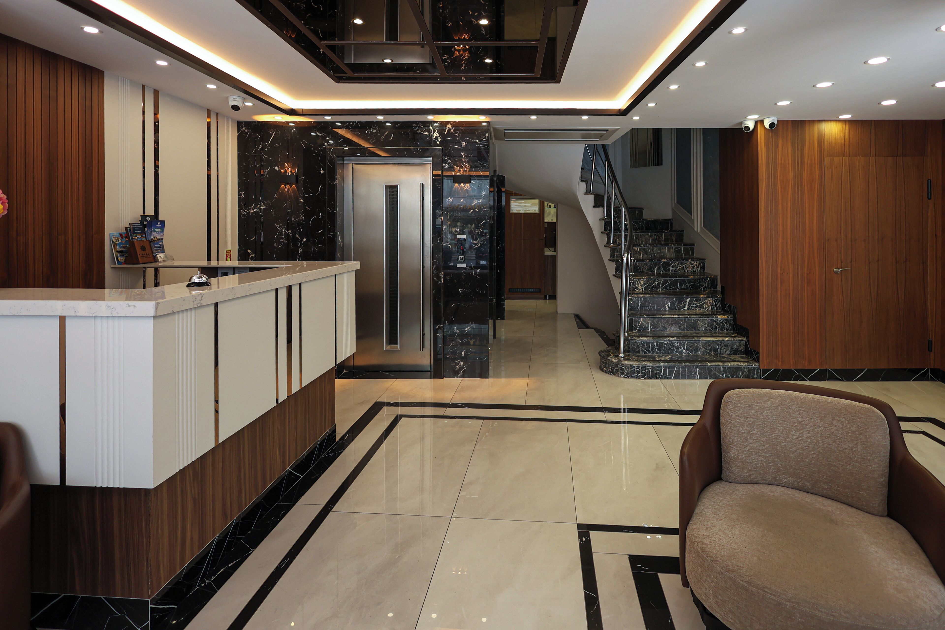 A modern lobby with a reception desk, a staircase, and a seating area.