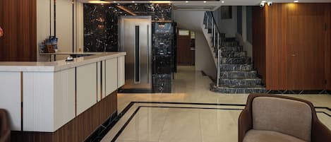 Un vestíbulo moderno con mostrador de recepción, una escalera y un área de estar.