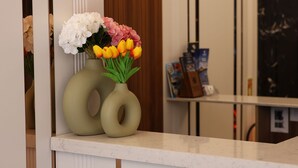 A reception desk with a vase of flowers, a magazine rack, and a wooden panel wall. - Kalkan Hotel (Istanbul)
