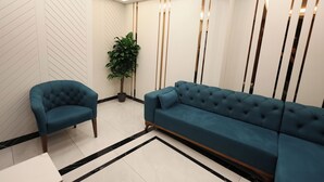 A modern interior with a blue sofa and armchair, a potted plant, and a decorative wall with vertical lines. - Kalkan Hotel (Istanbul)