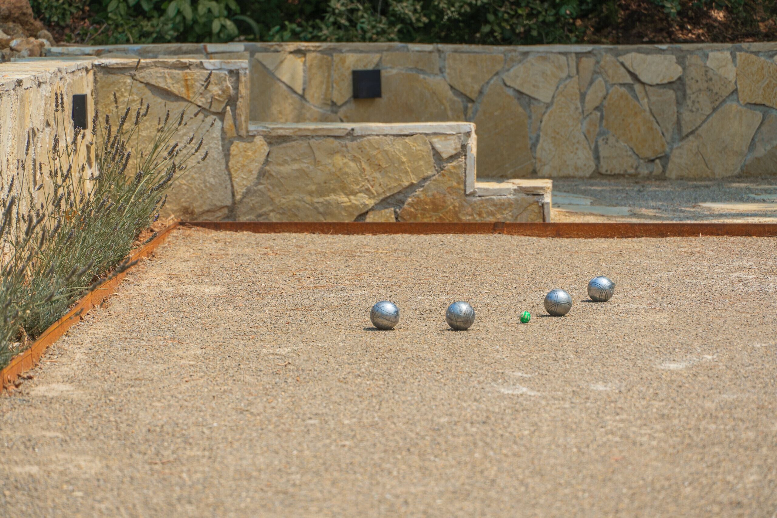 A courtyard with a gravel surface, a stone wall, and a metal fence.