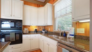 A kitchen with white cabinets, a stainless steel sink, a microwave, and a coffee maker. - The Perch - Big Canoe, GA (Big Canoe)