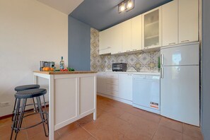 Eine Küche mit weißen Schränken, einer eingebauten Mikrowelle und einem weißen Kühlschrank.