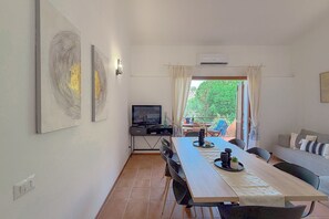 Ein Essbereich mit einem langen Tisch, Stühlen, einem Fernseher und Kunstwerken an den Wänden.