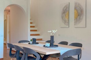Un coin repas avec une table en bois, des chaises noires et un vase rempli de fleurs. Des tableaux abstraits ornent le mur.