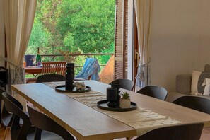 Ein Essbereich mit einem Holztisch, Stühlen und Blick auf grüne Vegetation.