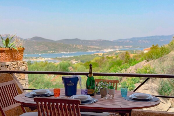 Un espace de restauration en plein air avec une table dressée pour deux personnes, offrant une vue sur un paysage pittoresque.