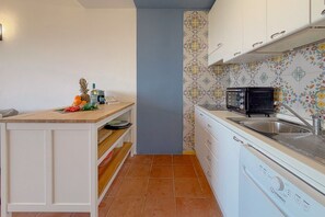 A compact kitchen with white cabinetry, a microwave, a dishwasher, and a tiled backsplash. - Sea View over Portisco Bay - Spacious 3BR Home - Clima (Porto Rotondo)