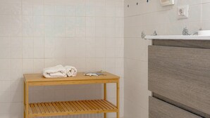 Kylpyhuoneessa on puinen pöytä, pyyheteline ja pesuallas, jonka alla on puinen kaappi.