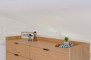 Une commode en bois avec des tiroirs, un tableau encadré et des objets décoratifs posés sur le dessus.