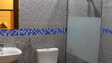 Un baño con pared de azulejos, un lavamanos, un inodoro y una cabina de ducha.