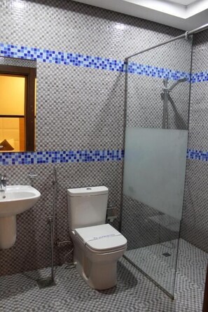 Een badkamer met betegelde wanden, een wastafel, toilet en douchecabine.