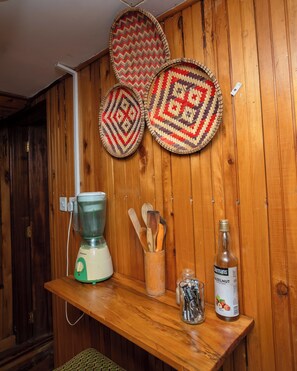 Una cocina con pared de madera, una licuadora, un tarro de avellanas y una botella de almíbar de avellana.