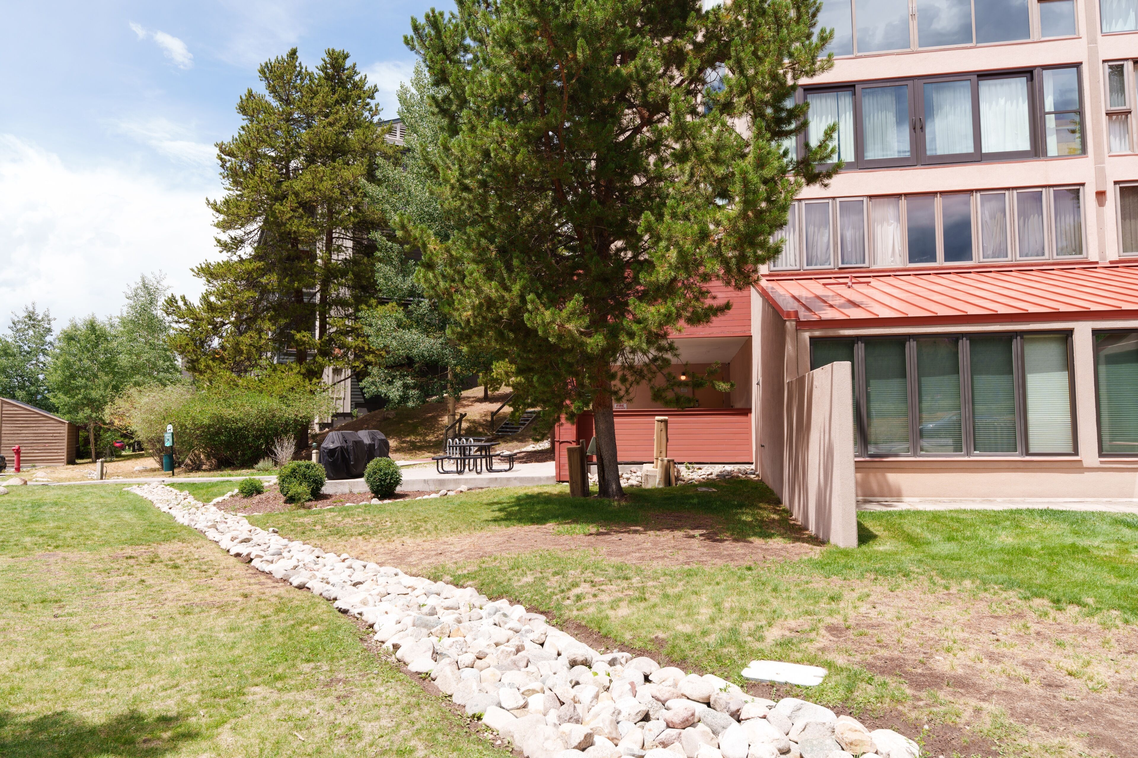 Un edificio con techo rojo, un sendero de piedra y un área verde con árboles.