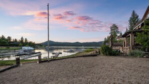 A lakeside property with a sandy beach, docked boats, and a mountain in the background. - NEW Lakefront (Location, about the cabin, game room, and more!) (Big Bear Lake)