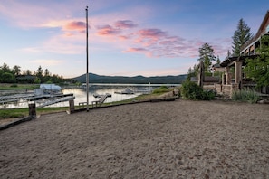A lakeside property with a sandy beach, docked boats, and a mountain in the background. - NEW Lakefront (Location, about the cabin, game room, and more!) (Big Bear Lake)