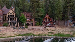 A lakeside lodge with a dock, multiple buildings with distinct architectural styles, and a natural forest backdrop. - NEW Lakefront (Location, about the cabin, game room, and more!) (Big Bear Lake)