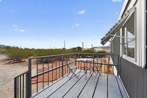 Eine Terrasse mit Metallgeländer, Tisch und Stühlen.