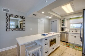 Una cocina moderna con encimera blanca, horno empotrado y refrigerador de acero inoxidable.