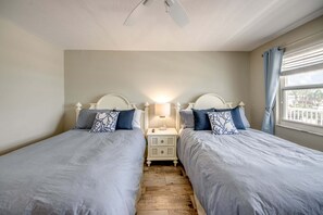 Een slaapkamer met twee enkele bedden, een nachtkastje met een lamp en een raam met gordijnen.