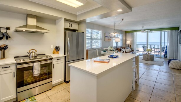 A modern kitchen with a central island, stainless steel appliances, and a view to the living area. - Beach Villas 101 Beachfront Condo: Heated Pool, Walk To Dwtn 2 Bedroom Condo (Fort Myers Beach)