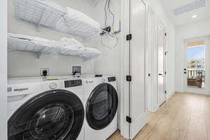 Un moderno cuarto de lavado con dos lavadoras Whirlpool, un tendedero y un sistema de ventilación.