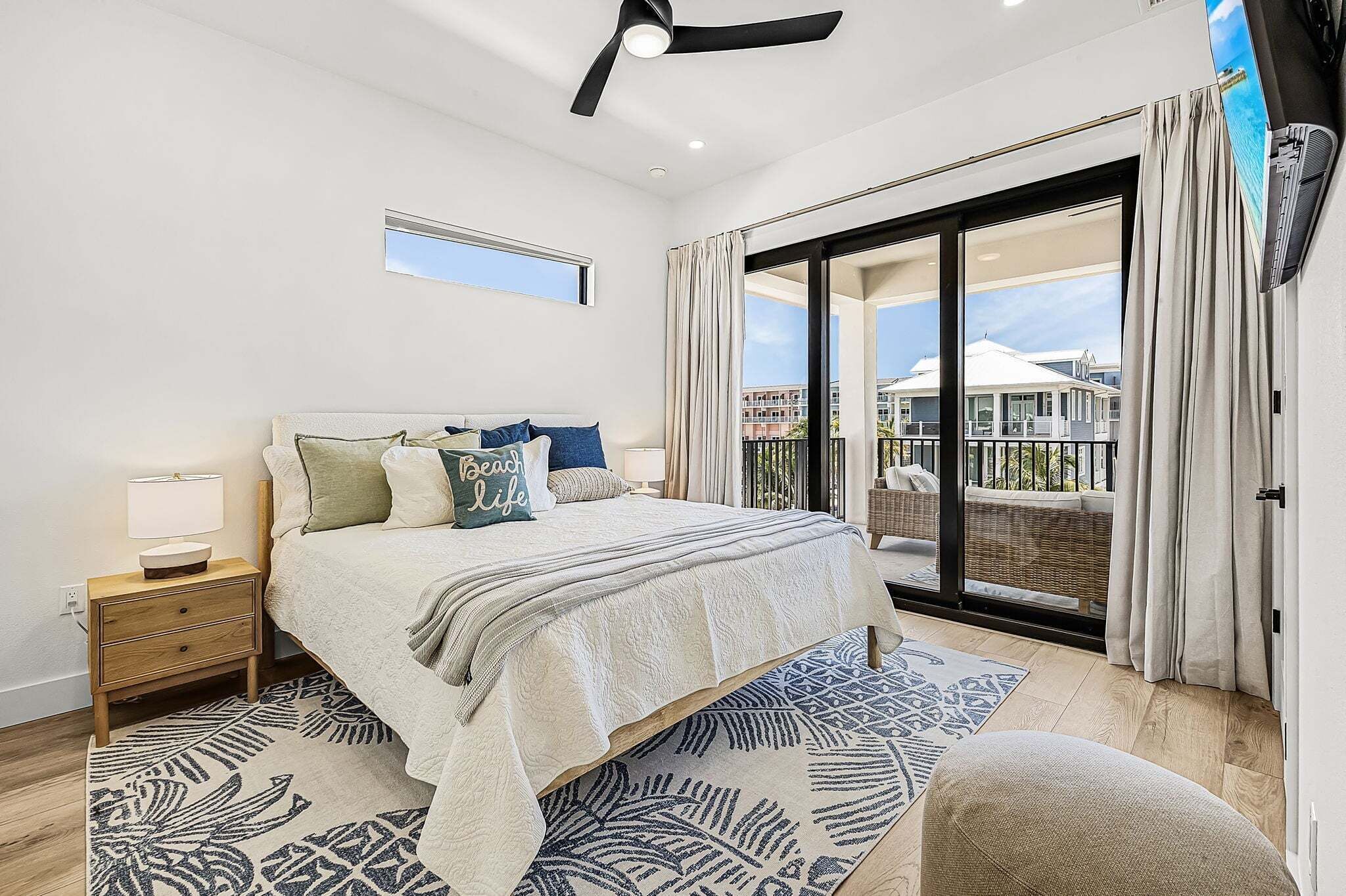 A bedroom with a bed, a nightstand, a window, and a view of a building through the window.