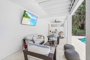 A sunlit patio with a pool, outdoor seating, and a ceiling fan. - 21188 Noddy Tern: 4br Home W/ Pool 4 Bedroom Home (Fort Myers Beach)