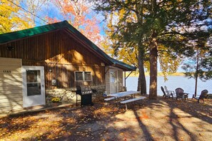 Eine Holzhütte mit Steinfundament und einem Steg, der in einen See führt.