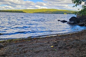 Un lac aux rives rocheuses, avec une colline boisée en arrière-plan.