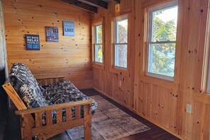 Ein Holzblock-Interieur mit einer Couch, zwei Fenstern und an der Wand befestigten Schildern.
