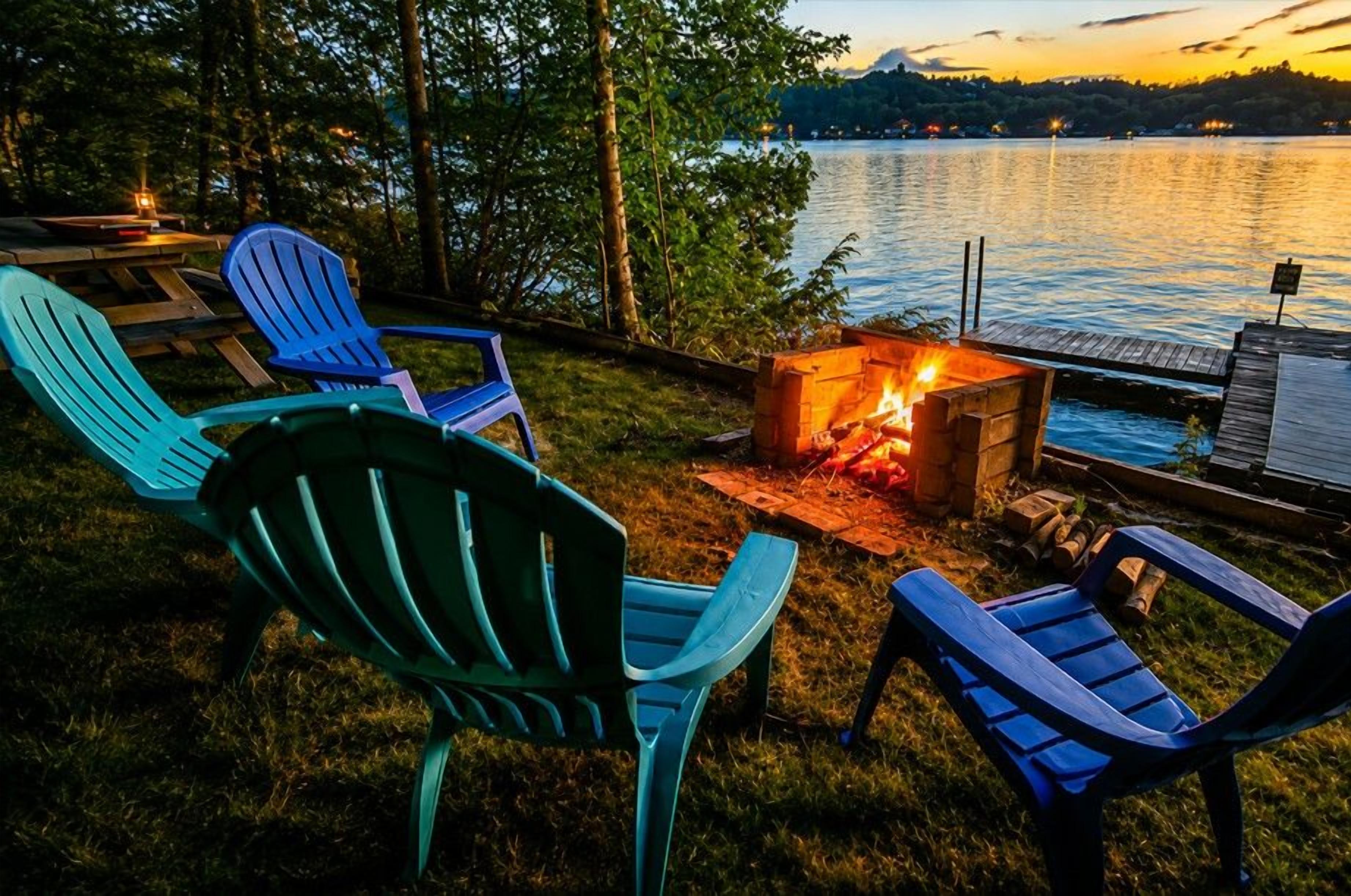 A lakeside outdoor seating area with Adirondack chairs and a fire pit.