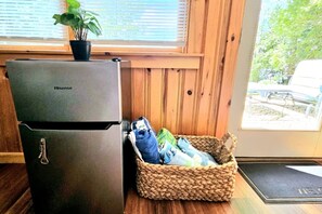 A compact kitchen with a Hisense refrigerator, a woven basket with clothes, and a view of the outdoors through a window. - Great Pond Getaway|Lakefront|Dock|Sunset Views (Belgrade)