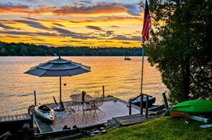 Ein Steg am See mit Tisch und Stühlen, einem Kanu und einer amerikanischen Flagge.