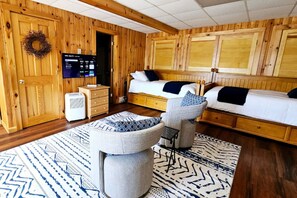 Ein gemütliches Zimmer mit Holzwänden, einem Bett, einem Schreibtisch und einem Stuhl.