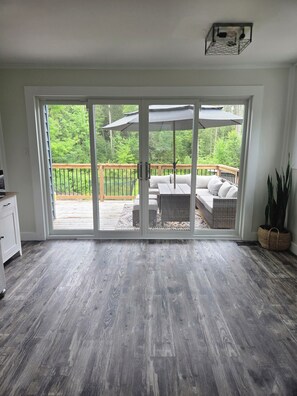 A room with a sliding glass door leading to an outdoor deck with a sofa and umbrella.