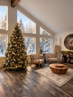 Una sala de estar acogedora con un gran árbol de Navidad, una chimenea adornada con calcetines y un reloj de pared rústico.