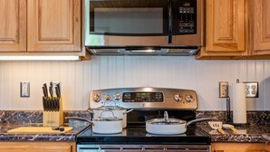 Eine Küche mit Holzausstattung, einer Edelstahl-Mikrowelle, einem Backofen und einer Arbeitsplatte aus Granit.