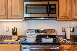 A kitchen with wooden cabinets, a stainless steel microwave, an oven, and a granite countertop.