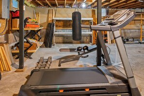Un gimnasio en casa con cinta de correr, pesas y saco de boxeo.
