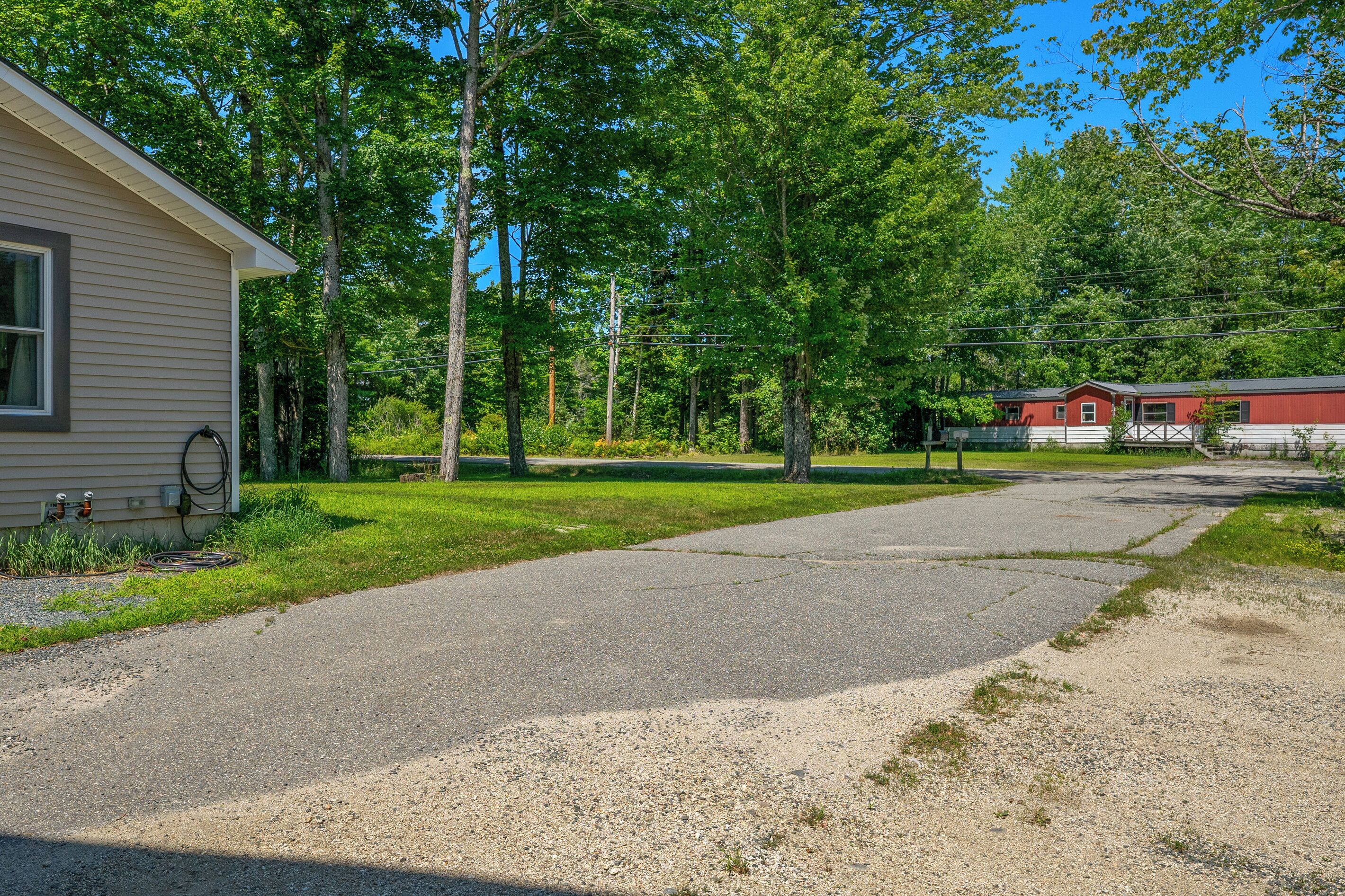 A residential area with a gravel driveway leading to a house with a garage.
