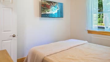 Ein Schlafzimmer mit einem Bett, einem Bild an der Wand und einem Fenster mit Vorhängen.