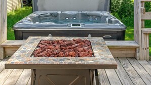 Ein Whirlpool mit einer gefliesten Umrandung und einem Feuerkorb im Vordergrund.