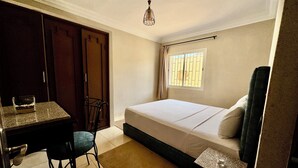 A bedroom with a bed, a desk, a chair, a window, and a hanging light fixture. - HOTEL BEACH CLUB LA PERLE (Casablanca)