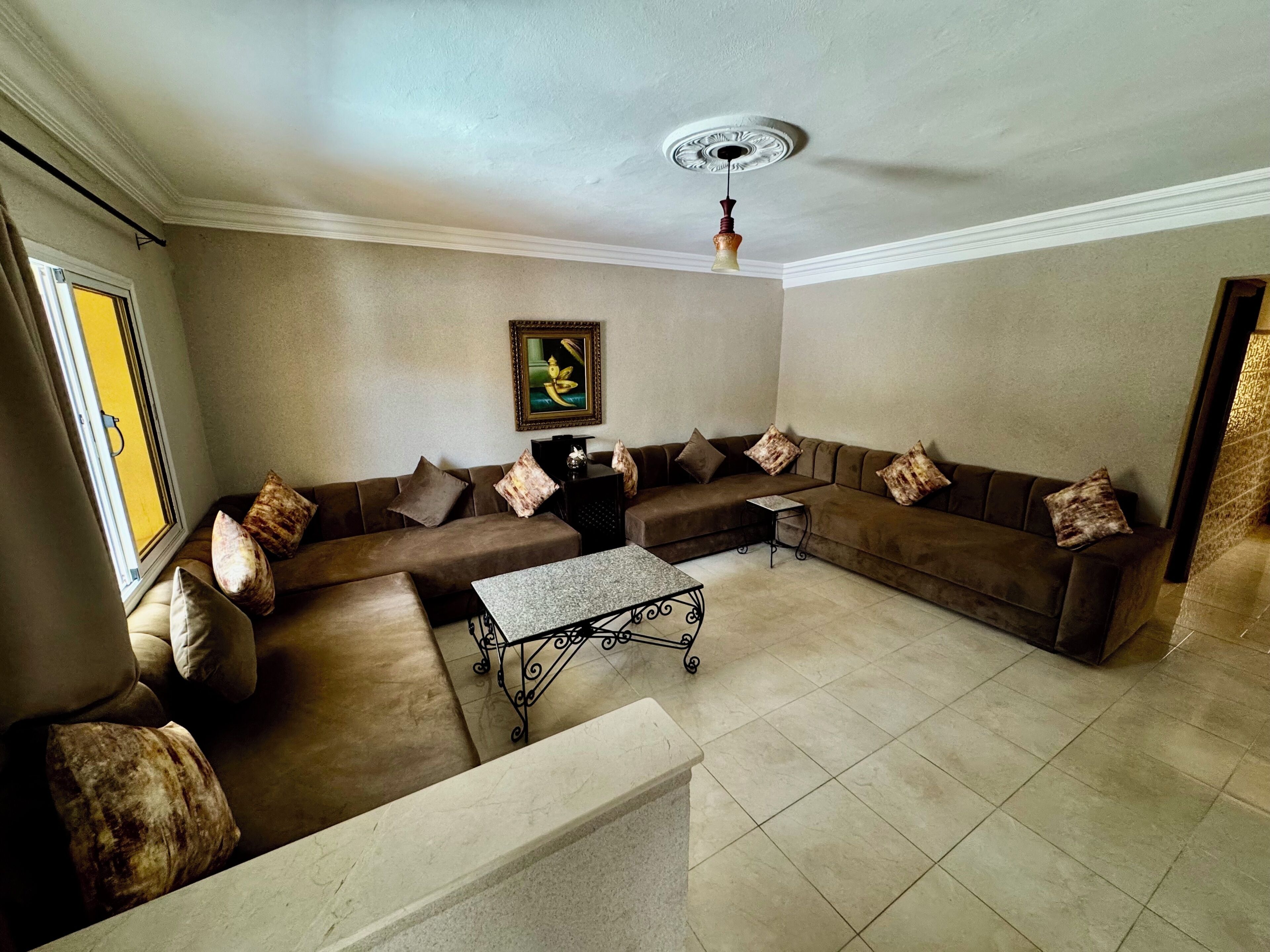 Ein Wohnzimmer mit einem Ecksofa, einem Couchtisch und einem Deckenventilator.