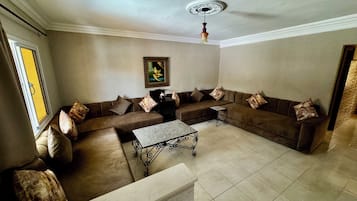 Ein Wohnzimmer mit einem Ecksofa, einem Couchtisch und einem Deckenventilator.