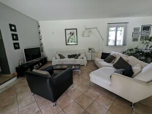 A living room with a flat-screen TV, two sofas, a coffee table, and a floor lamp. - A very shady villa with a pool and a large garden featuring 29 oak trees. (Pélissanne)