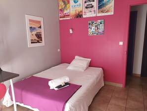 Ein Zimmer mit einem Bett, einem Tisch und einem Bild an der Wand.